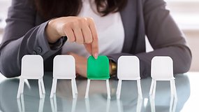 A person choosing a green seat in a row of white chairs