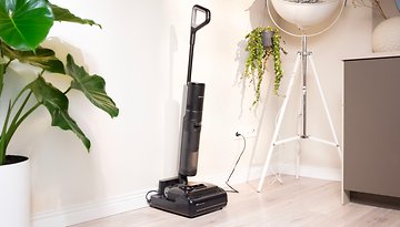 Ein Dreame H15 Pro Staubsauger steht neben einer Topfpflanze in einem modernen Interieur.