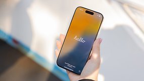Uma mão segurando um Apple iPhone 16 Pro exibindo uma tela colorida com 'olá'.