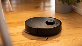 A black Ecovacs Deebot T30s Combo robot vacuum on wooden floor.