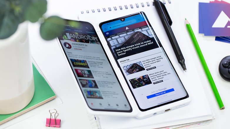 Two smartphones displaying websites on a desk with a notebook, a plant, and stationery. Two smartphones displaying websites on a desk with a notebook, a plant, and stationery.