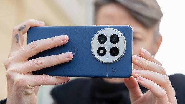 Une personne tenant un smartphone OnePlus 13 bleu avec trois caméras arrière, se concentrant sur la prise d'une photo.
