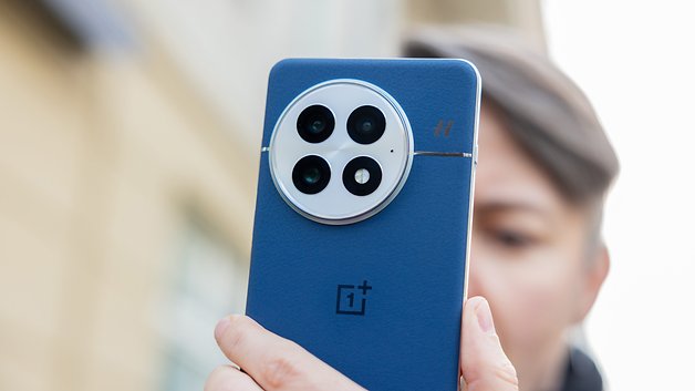 Une personne tenant le dos bleu d'un smartphone OnePlus 13, mettant en valeur son design de caméra.