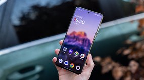 Eine Person hält ein OnePlus 13 Smartphone mit einem bunten Startbildschirm, der die Uhrzeit 15:50 anzeigt.