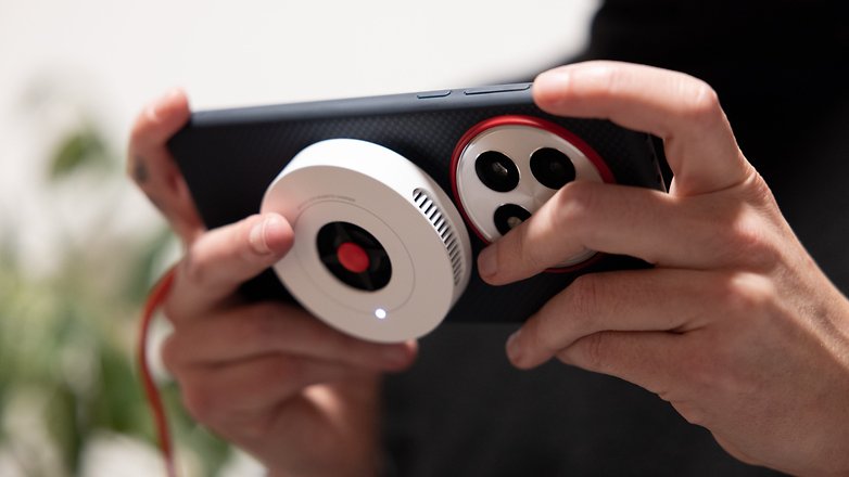 Une personne tenant un smartphone OnePlus 13 avec un accessoire photo. Une personne tenant un smartphone OnePlus 13 avec un accessoire photo.