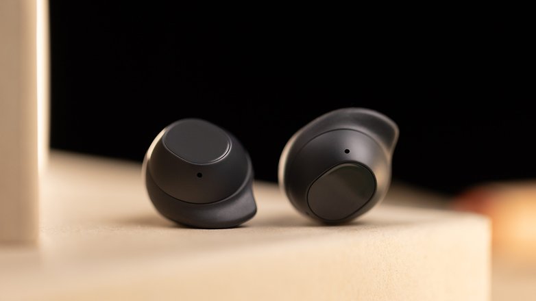Close-up dos Samsung Galaxy Buds FE em preto sobre uma superfície clara. Close-up dos Samsung Galaxy Buds FE em preto sobre uma superfície clara.