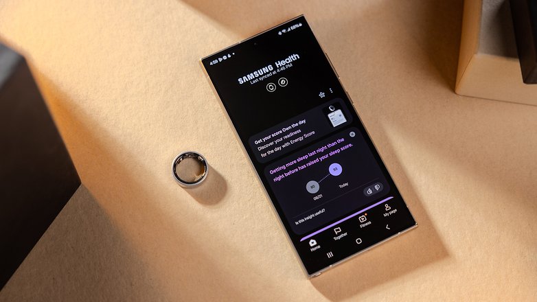 Um telefone Samsung Galaxy exibindo o aplicativo Samsung Health ao lado de um anel Samsung Galaxy. Um telefone Samsung Galaxy exibindo o aplicativo Samsung Health ao lado de um anel Samsung Galaxy.
