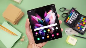 Uma pessoa segurando um smartphone Samsung Galaxy Z Fold 3 com aplicativos exibidos em um fundo colorido.