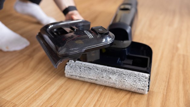 A person holds a removable part of the Tineco Floor One S7 vacuum cleaner over a wooden floor.The di