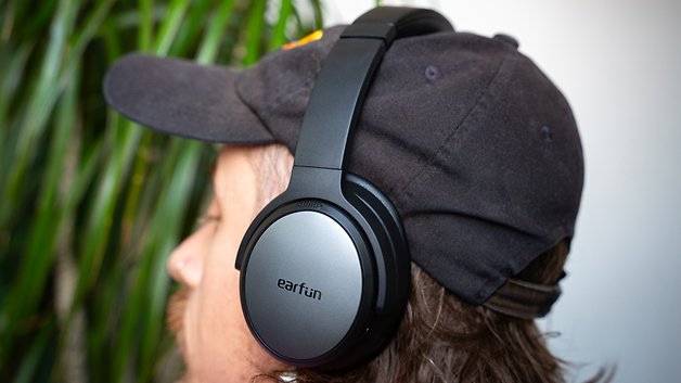 Ein Mann mit langen Haaren, der eine schwarze Mütze und EarFun Tune Pro Kopfhörer trägt.