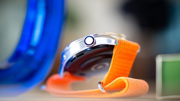 Close-up de um relógio Xiaomi S4 com uma pulseira laranja e caixa prateada.