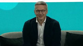 Karsten Wildberger lächelt, während er auf einem Sofa bei einer Konferenz sitzt.
