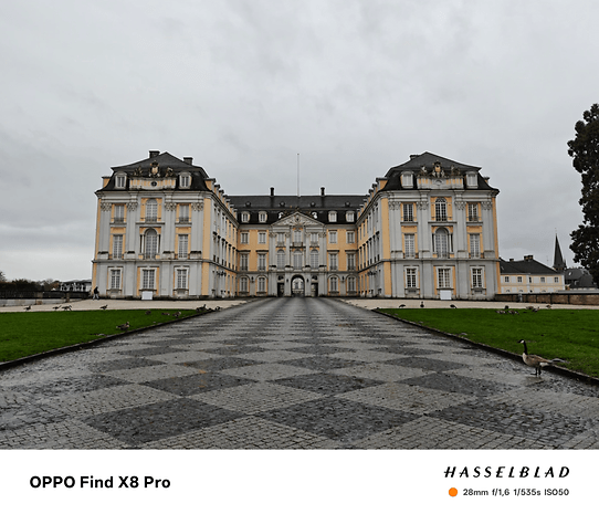 Un grand bâtiment historique avec des façades jaunes et blanches et un ciel nuageux au-dessus.
