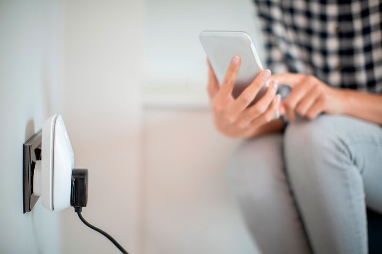 Contrôlez vos prises connectées via votre smartphone Une femme parametre une prise connectee avec son smartphone
