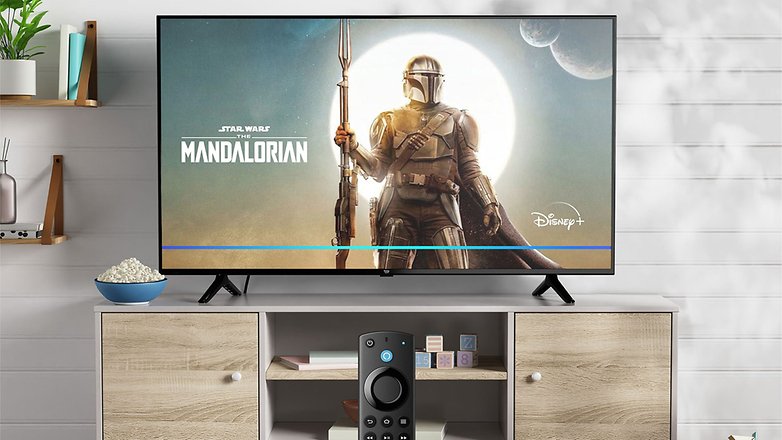 Der Amazon Fire TV-4 zeigt 'Star Wars: The Mandalorian' mit einer Fernbedienung darunter. Popcorn in einer Schüssel daneben. Der Amazon Fire TV-4 zeigt 'Star Wars: The Mandalorian' mit einer Fernbedienung darunter. Popcorn in einer Schüssel daneben.