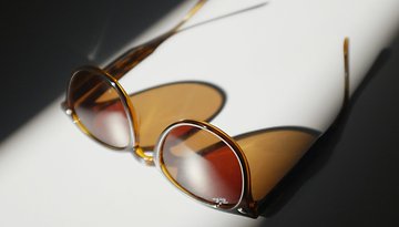 Sunglasses on a white surface, highlighted by soft shadows.